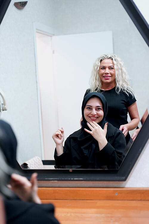 A happy client seeing the result in the mirror with her stylist