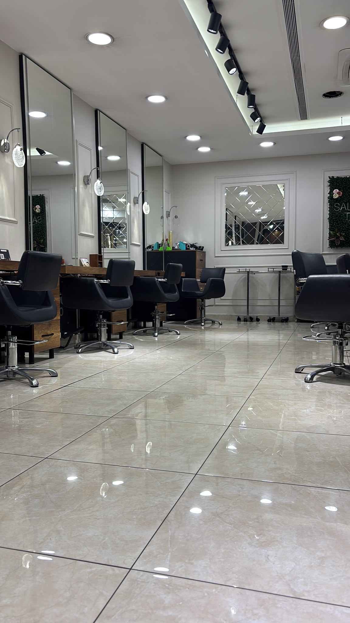 The row of mirror stations running the length of the salon, with black track lighting